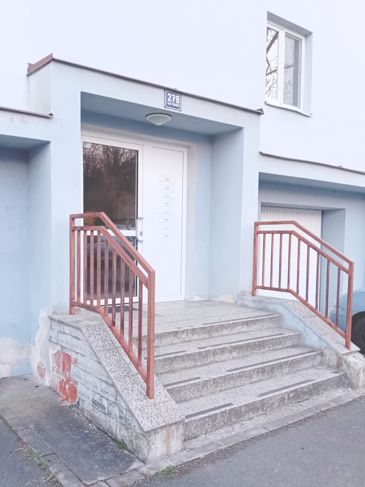 Staré vstupní schody s červeným zábradlím